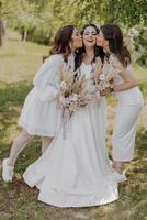 Three women are posing for a picture, one of them is wearing a white dress photo