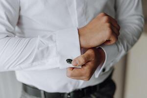 A man is getting dressed in a white shirt and black pants photo