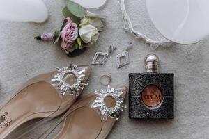 A pair of high heels, a bottle of perfume, and a flower are displayed on a table photo