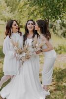 Three women are posing for a photo, with one of them wearing a white dress photo