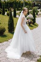 A bride is walking down a path with a bouquet of flowers in her hand photo