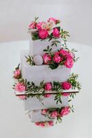 A three tier cake with pink flowers and pink frosting photo