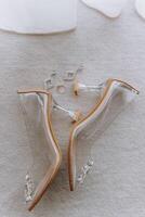 A pair of clear high heels with a diamond ring on the left photo