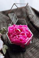 A pink flower with two rings on it is in a glass container photo
