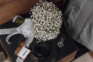 un ramo de flores de blanco flores se sienta en un mesa siguiente a un reloj y un caja foto