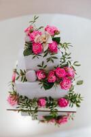 A three tier cake with pink flowers and a white and pink orchid on top photo