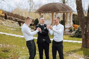 Three men in suits are standing in a grassy area photo