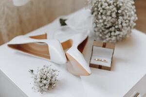 A pair of white shoes and a white flower arrangement sit on a table photo