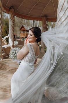 A bride is posing for a picture with a veil blowing in the wind photo