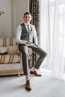 A man in a suit and vest sits on a couch with his feet up photo