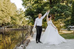 A bride and groom are walking down a path with a railing on either side photo