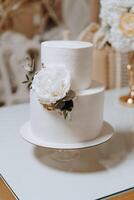 A white cake with a flower on top and a green leaf on the side photo