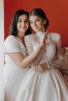 A woman in a wedding dress is hugging another woman photo