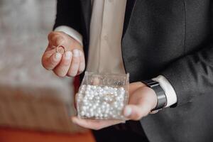 A man is holding a ring in a clear container photo