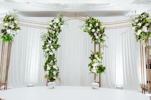 A white archway with flowers and a gold frame photo
