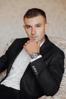 A man in a suit and white shirt is sitting on a couch photo