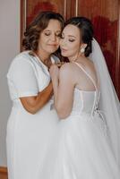 A bride and her mother are hugging each other photo