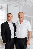 Two men are standing next to each other, one wearing a suit photo