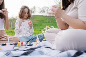 A young girl is sitting on a blanket with her mother and another woman photo