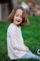 A young girl is sitting on the grass with a smile on her face photo