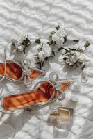 A pair of red high heels with a bow on the front are on a bed with a bottle of p photo