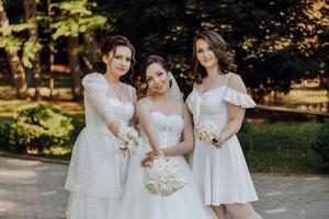 Three women in white dresses are posing for a photo