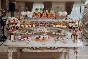 A table with a variety of desserts and drinks, including fruit and wine glasses photo