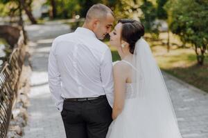 A bride and groom are standing on a bridge, smiling at the camera photo