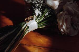 A bouquet of flowers with a white ribbon and two gold wedding rings photo