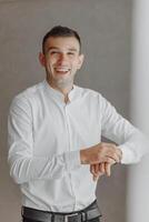 A man in a white shirt is smiling and wearing a watch photo