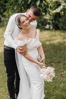 A bride and groom are hugging and smiling in a field photo