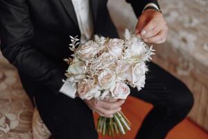 A man in a suit holding a bouquet of white flowers photo