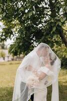 A couple is kissing under a white veil photo