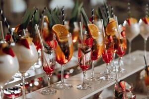 A table full of drinks with a variety of fruit garnishes and straws photo