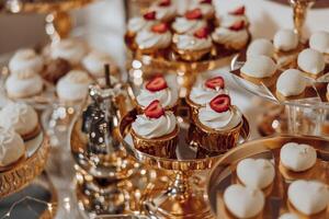 un mesa lleno de postres, incluso magdalenas y pasteles con fresas en parte superior foto