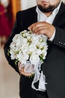 A man in a suit holding a bouquet of white flowers photo