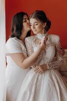 A woman in a wedding dress is hugging another woman photo