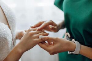 A woman is getting her wedding ring on her finger by another woman photo