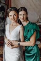 Two women are posing for a picture, one wearing a white dress photo