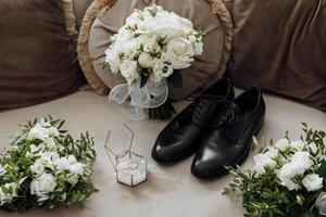 A black shoe and a white bouquet of flowers are displayed on a couch photo