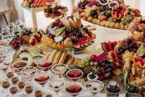 un mesa lleno de Fruta y bebidas, incluso vino lentes y martini lentes foto