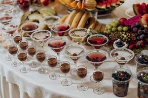 A table full of fruit and drinks, including a variety of cocktails and desserts photo