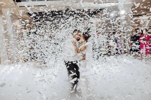 A bride and groom are dancing in a room full of confetti photo