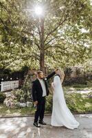 A bride and groom are dancing in front of a tree photo