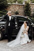 un hombre y un mujer son posando para un imagen en frente de un negro coche foto