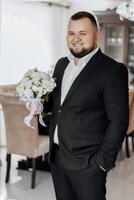 A man in a suit holding a bouquet of white flowers photo