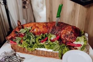 A large roasted pig is sitting on a table with a green knife sticking out of it photo