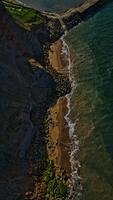 Aerial view of rocky coastline with cliff and breakwater photo