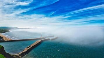 Aerial view of coastal pier with lighthouse and fog in Whitby, North Yorkshire photo