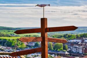 Wooden signpost with directional signs in scenic town in Whitby, North Yorkshire photo